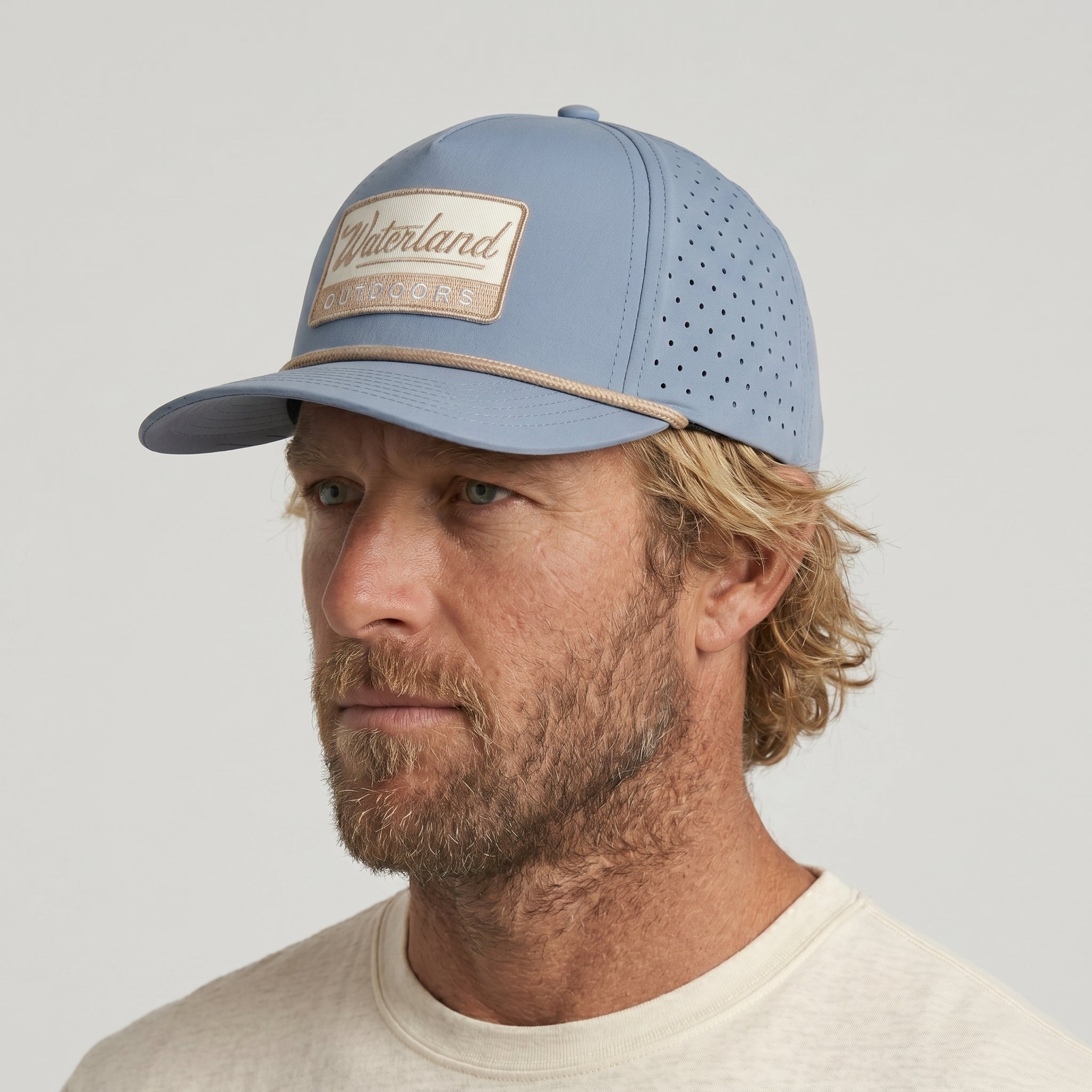 Man wearing a light blue baseball cap with a brand logo on a gray background