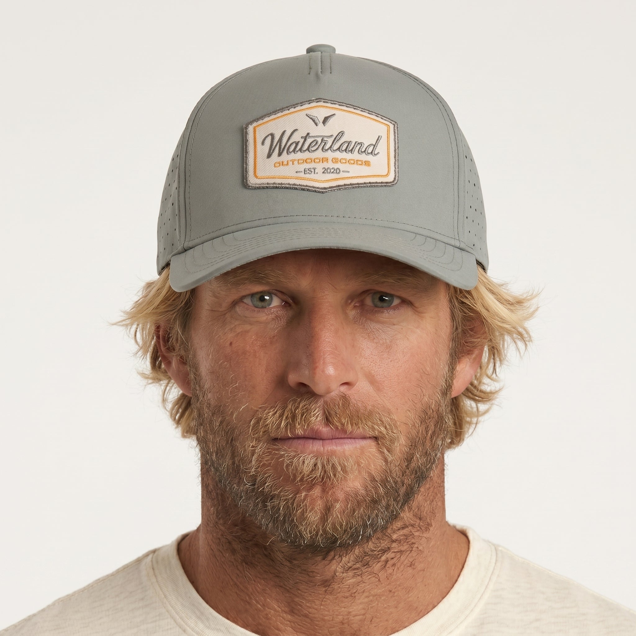 Man wearing a gray cap with a brand logo on a white background