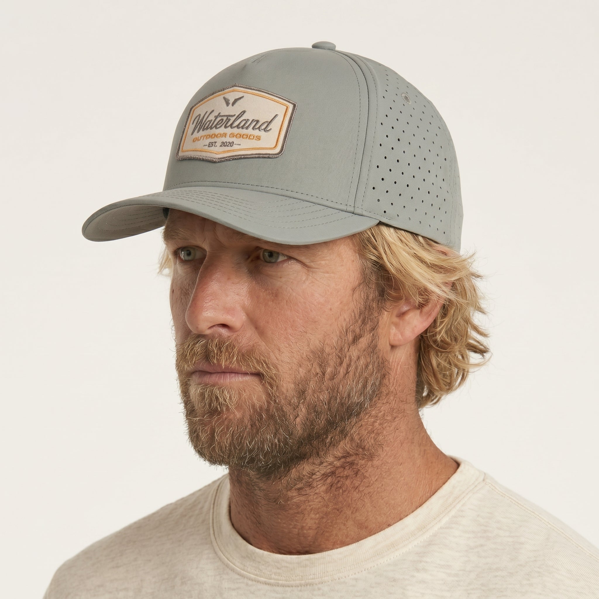Man wearing a gray cap with a visible brand logo on a beige background