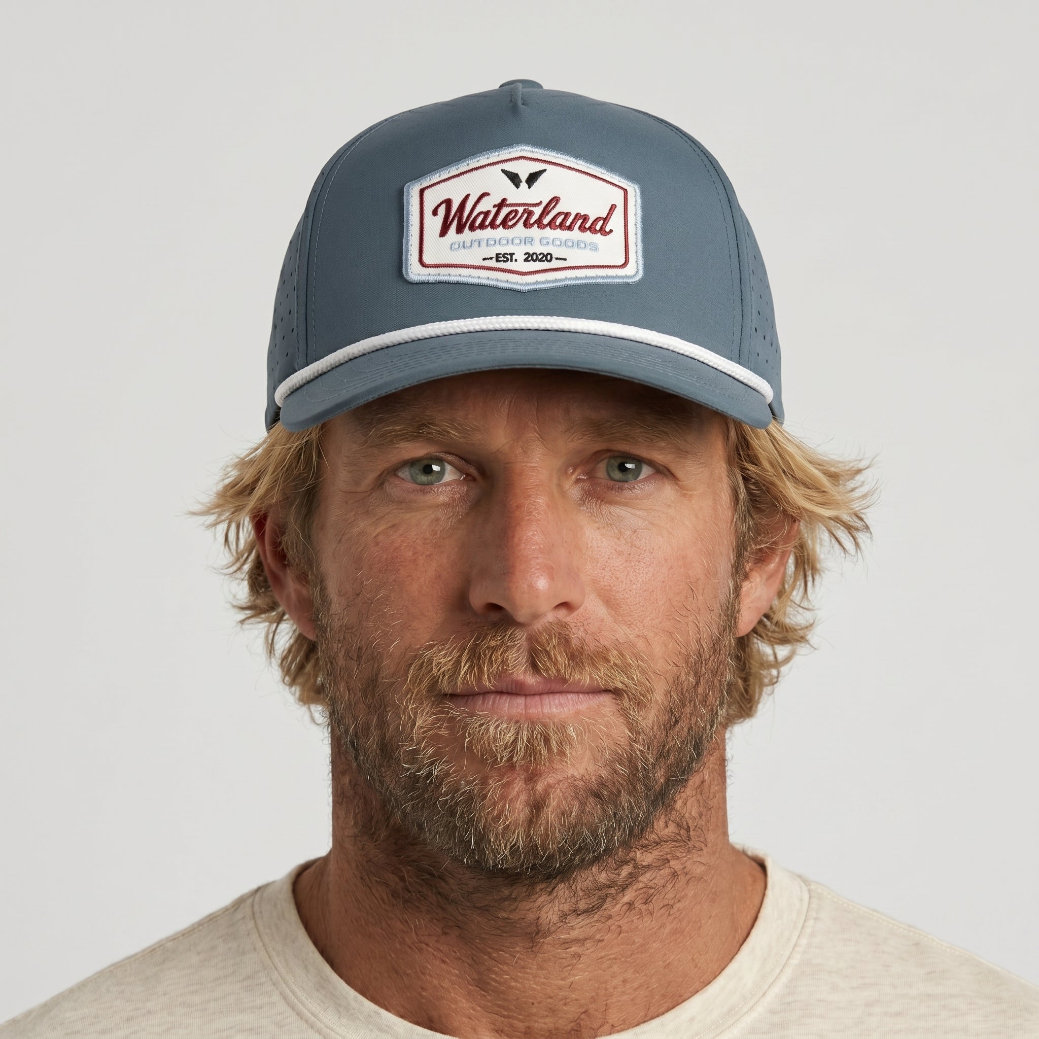 Man wearing a gray cap with a brand logo on a light gray background