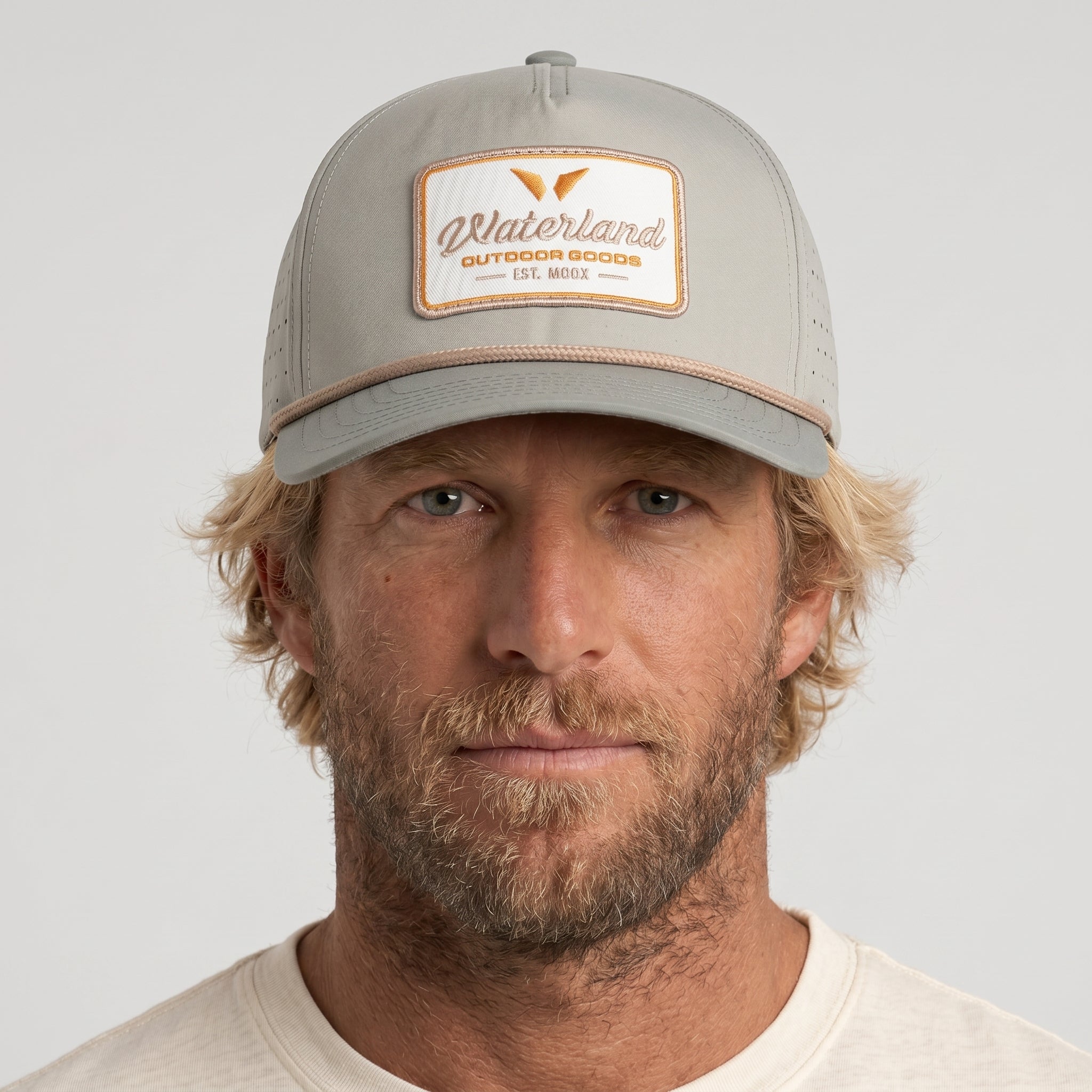 Man wearing a gray cap with a brand logo on a light gray background