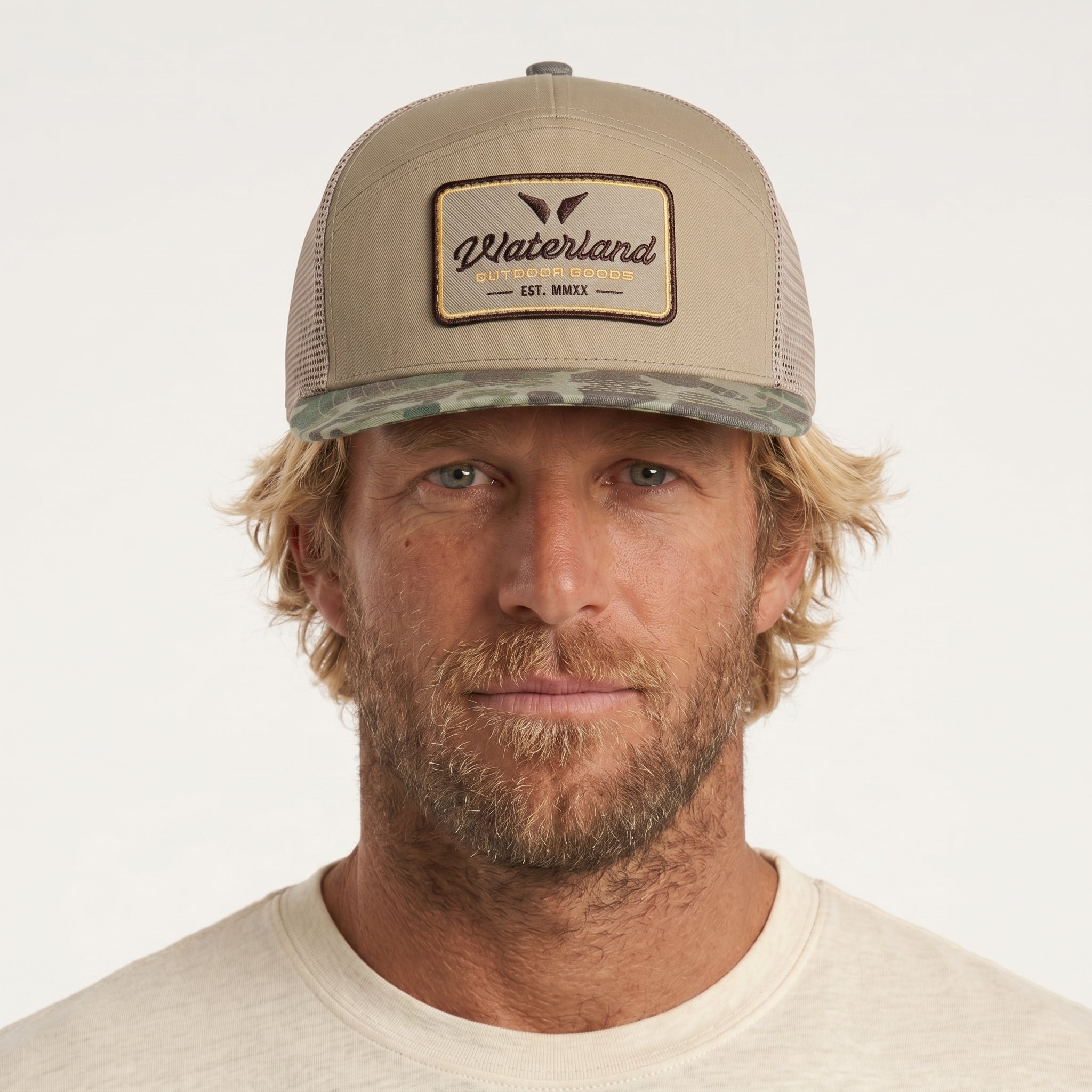 Man wearing a beige cap with a brand logo on a white background
