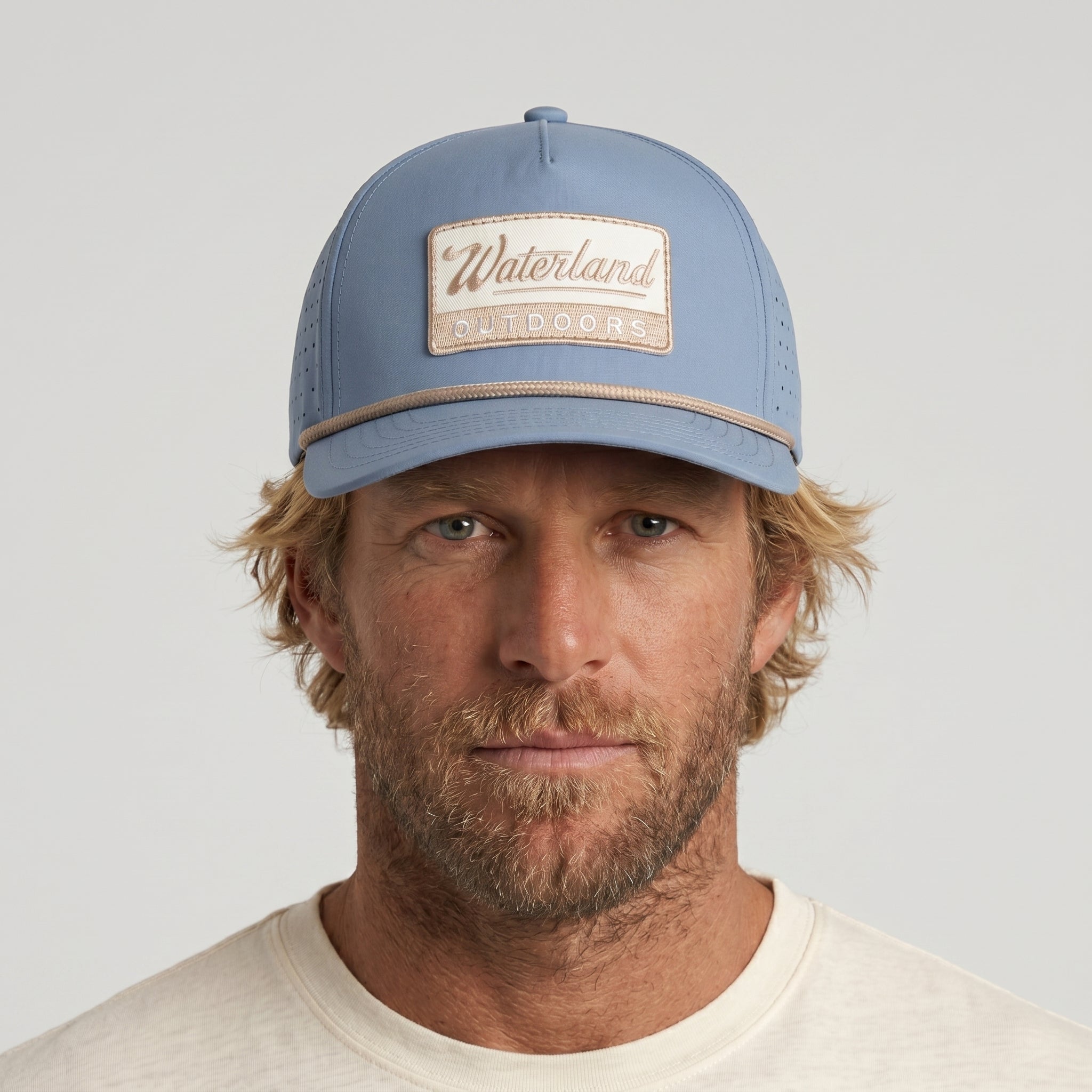 Man wearing a blue cap with 'Waterland' branding against a light gray background