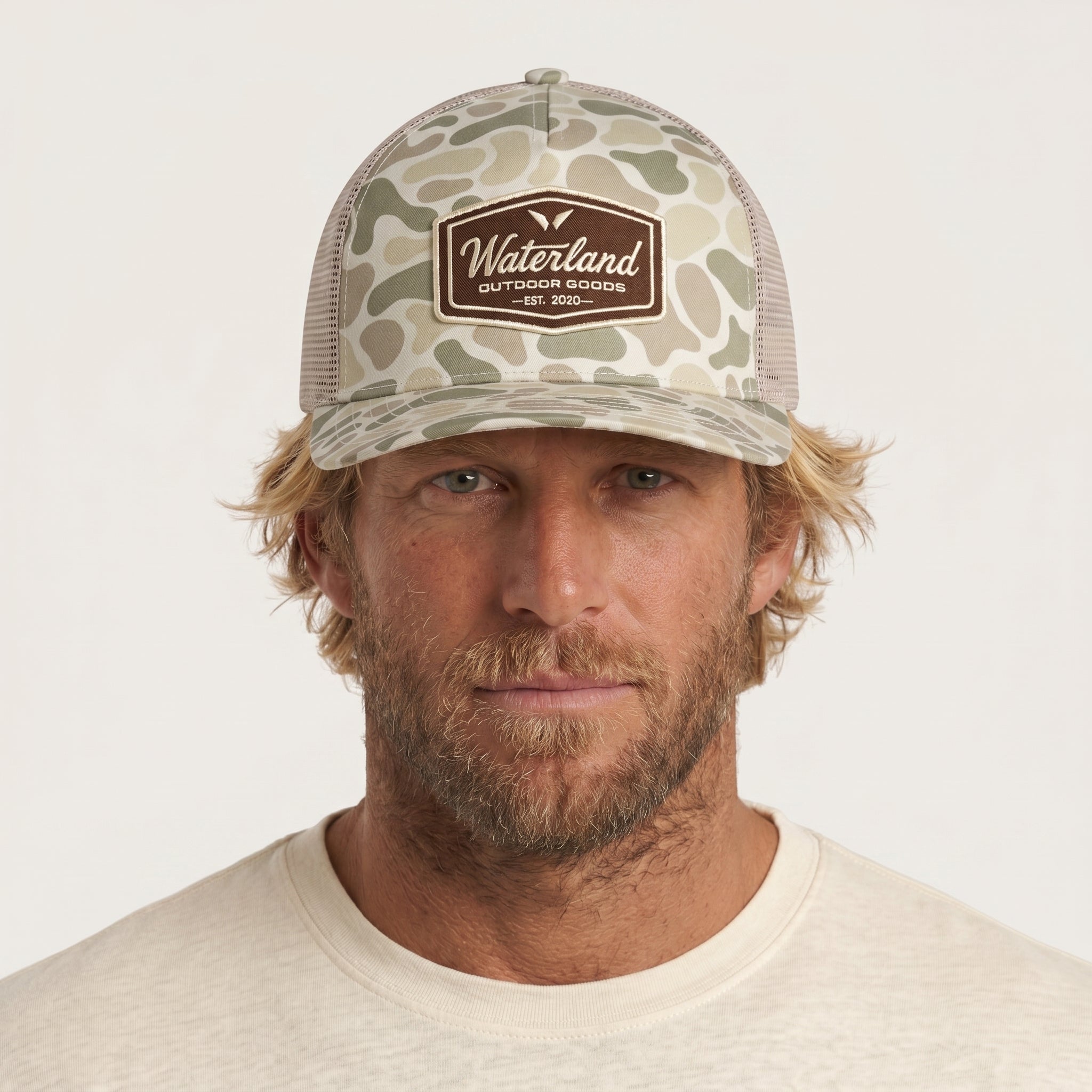 Man wearing a camouflage cap with 'Waterland' logo on a white background