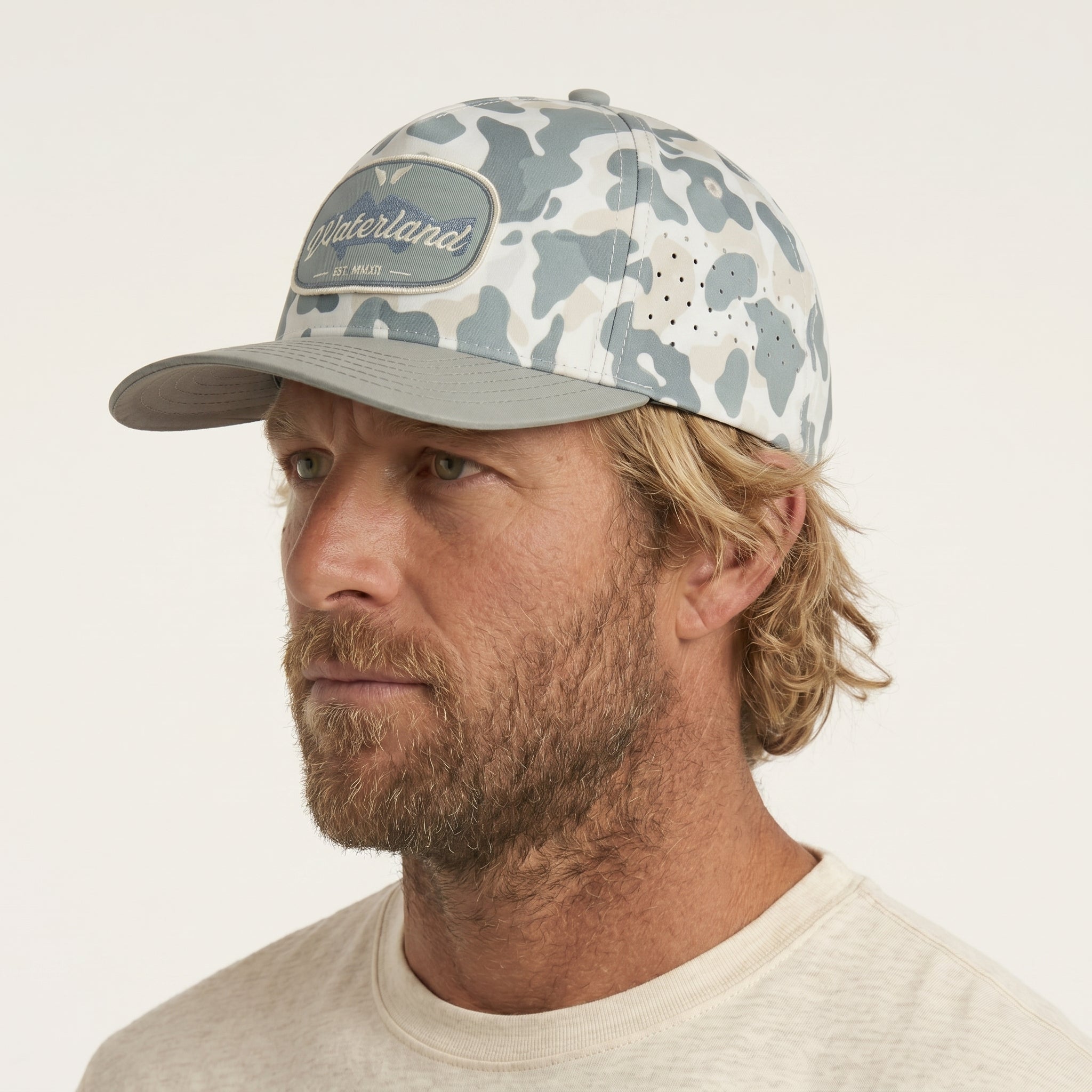 Man wearing a camouflage baseball cap on a plain background