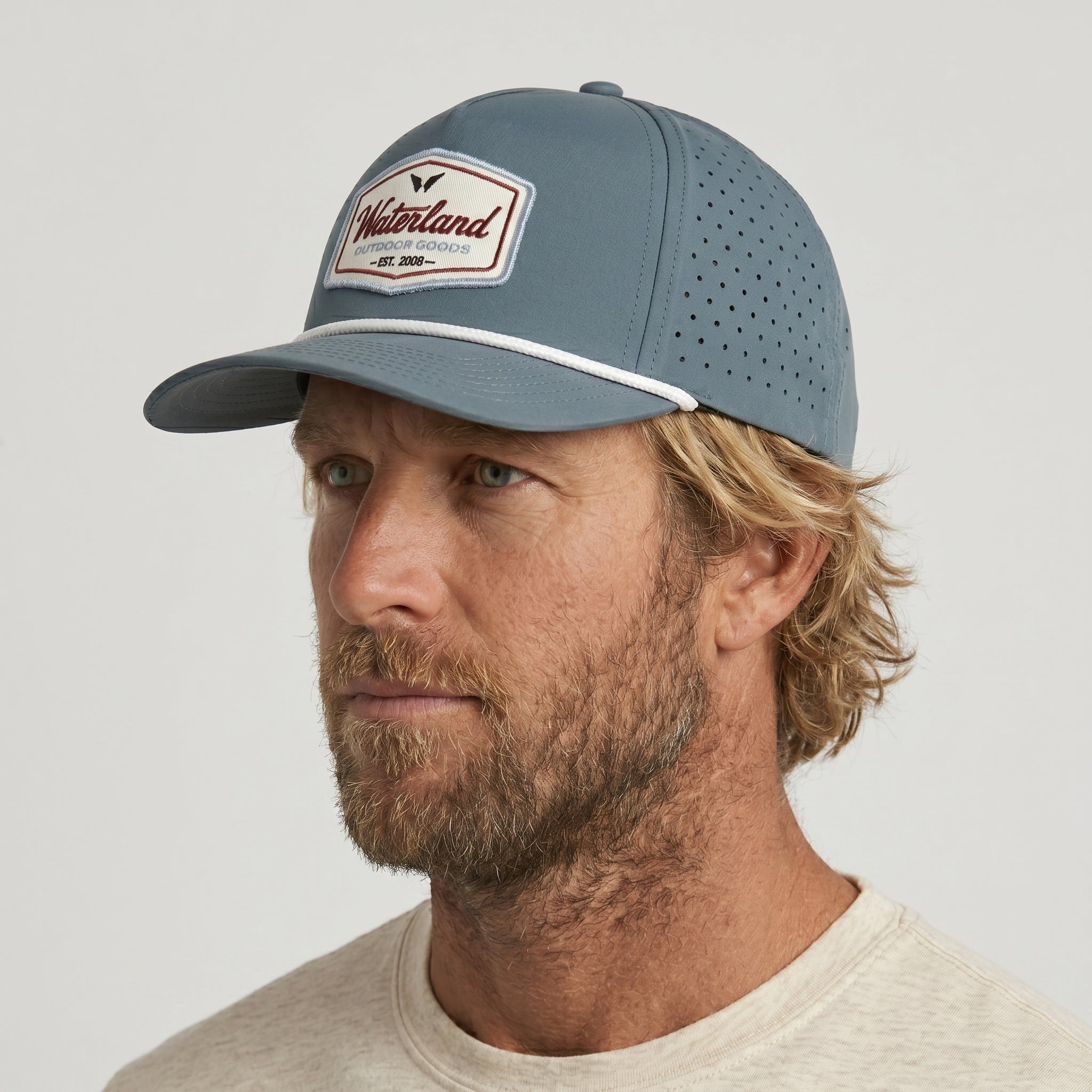 Man wearing a blue cap with a visible brand logo on a light gray background