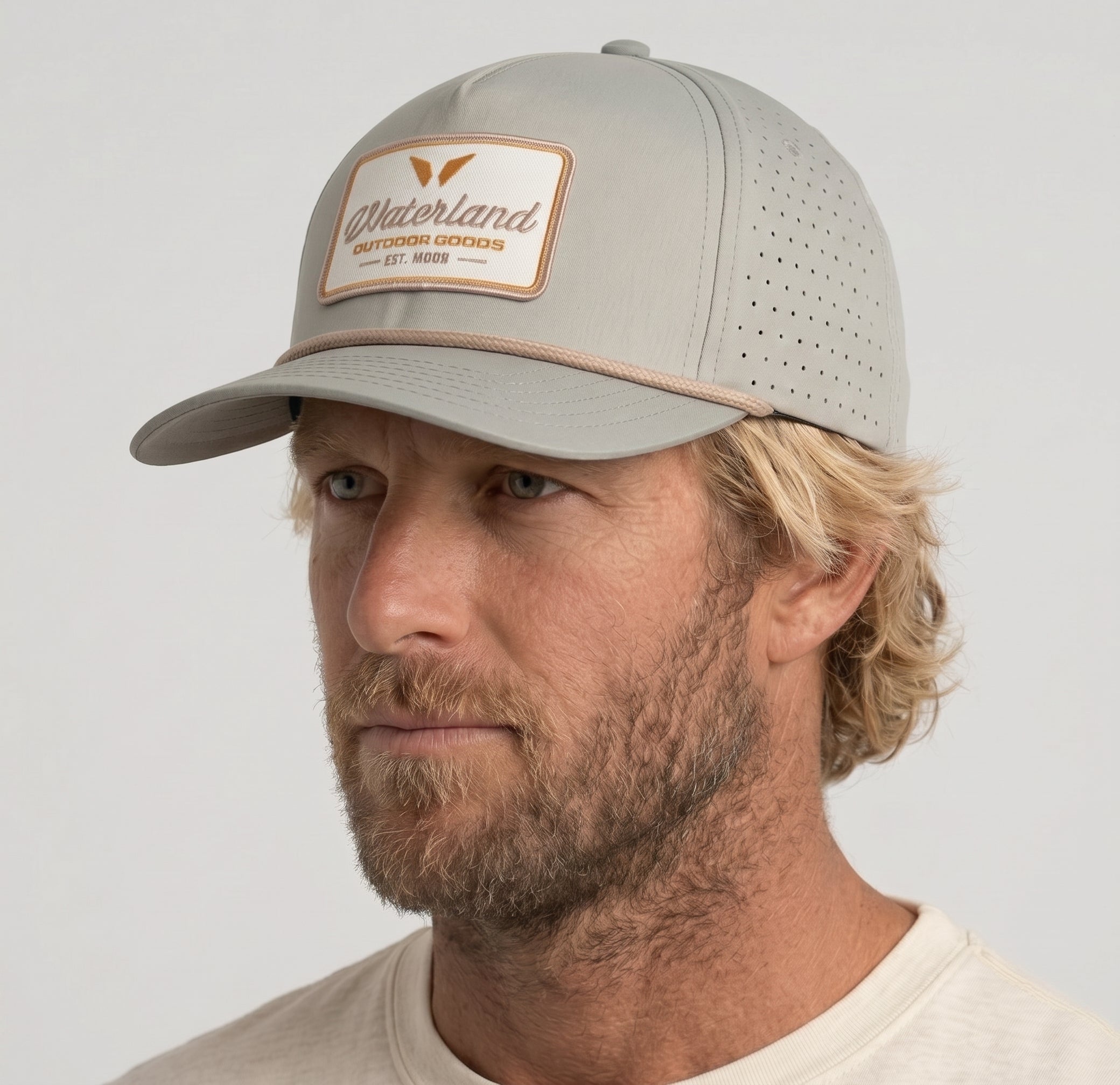 Man wearing a gray cap with a brand logo on a light gray background