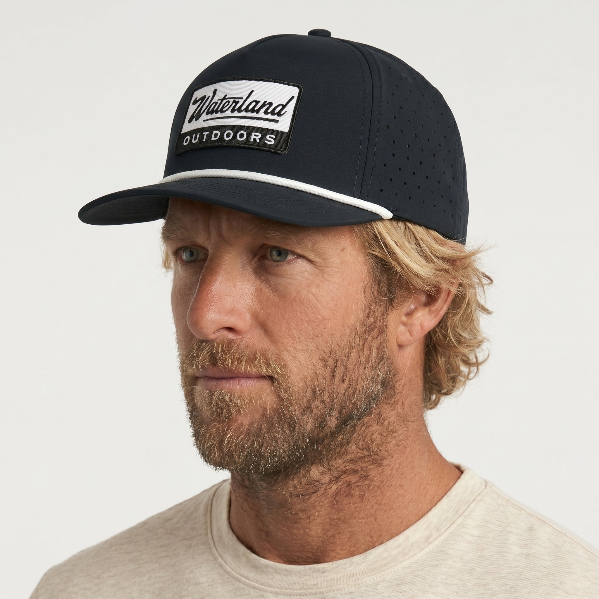 Man wearing a black cap with 'Waterland Outdoors' logo on a light gray background