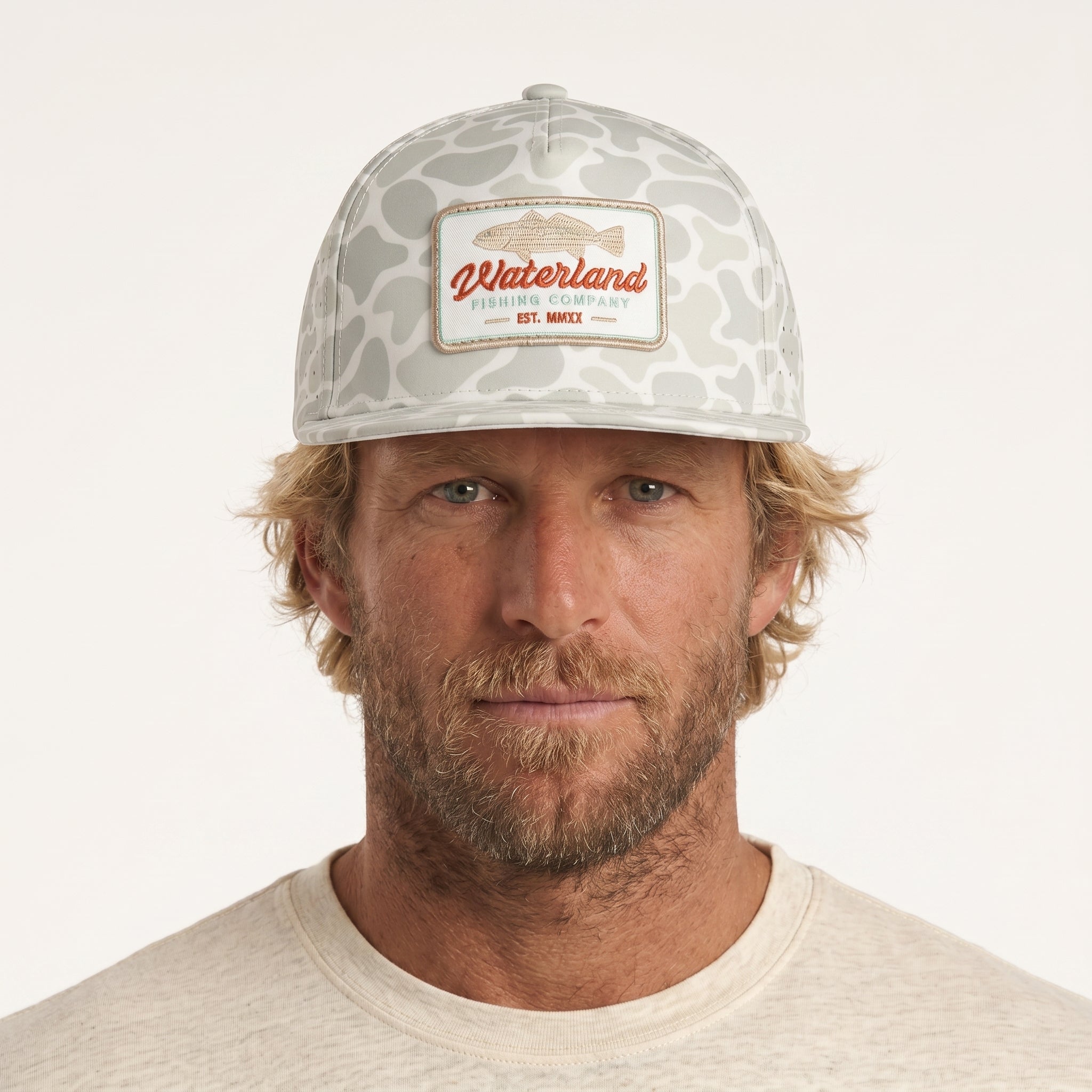 Man wearing a camouflage cap with a brand logo on a white background