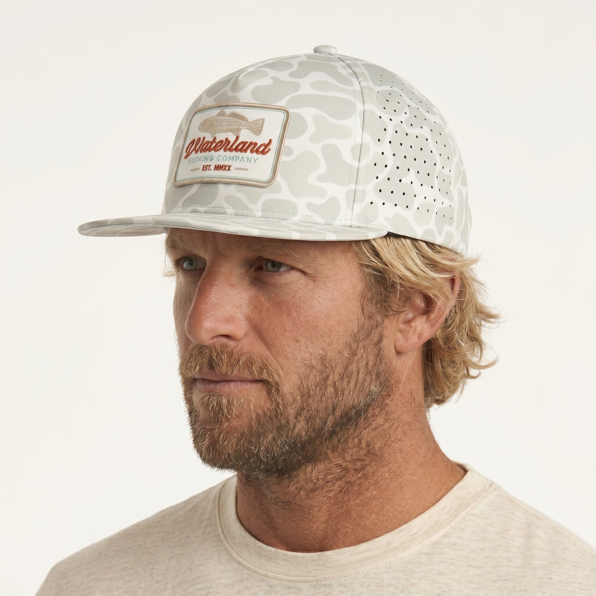 Man wearing a camouflage cap with a brand logo on a white background